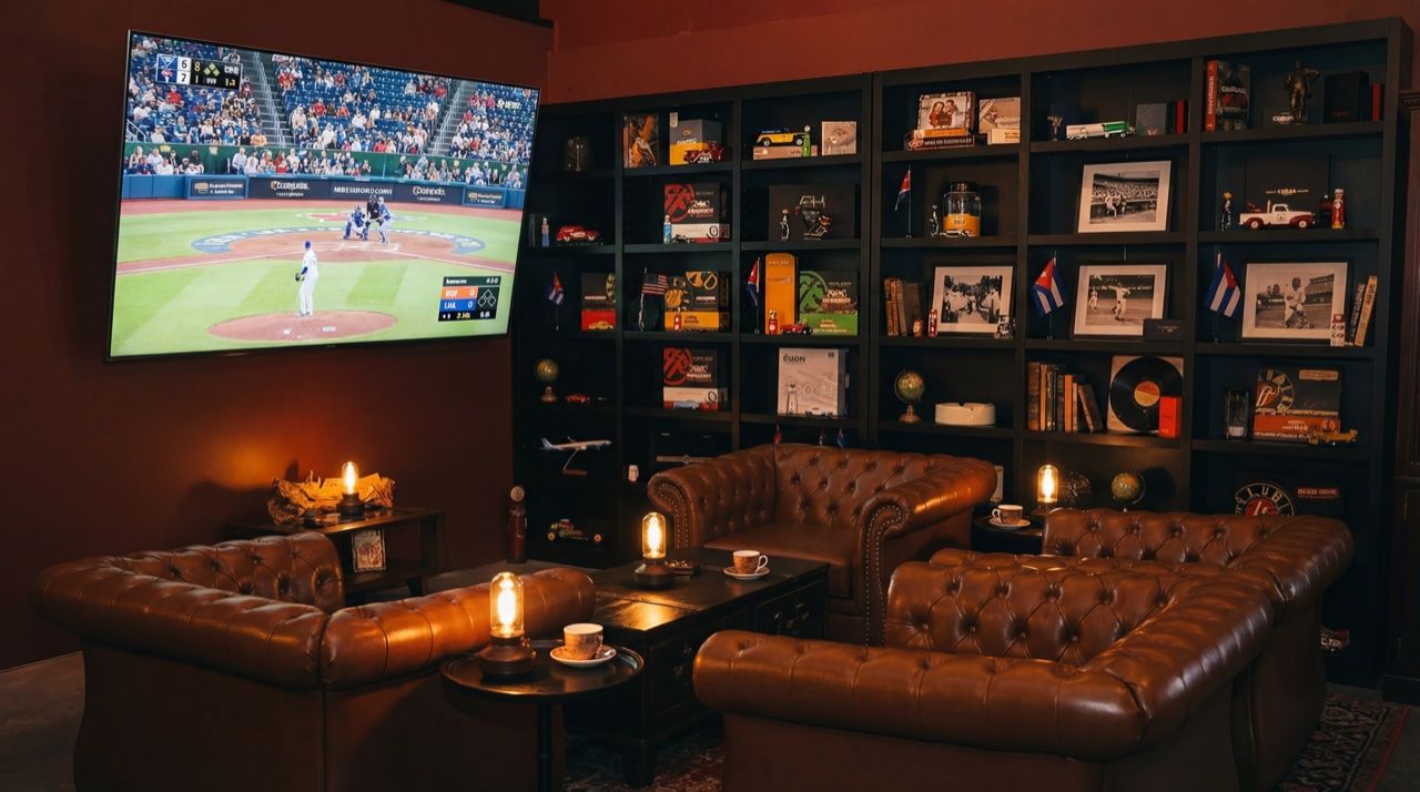 Big screen TV showing a live baseball game with leather seating and Cuban memorabilia shelves